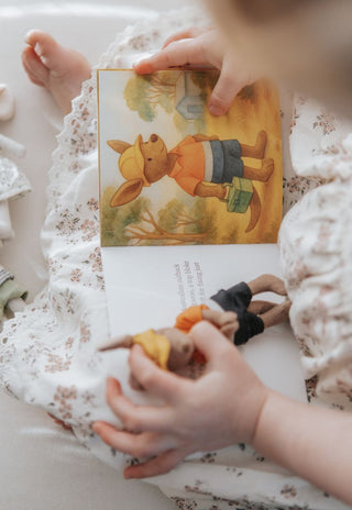 Child holding a kangaroo doll while reading The Tradie and the Broken Friend