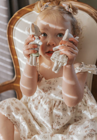 Little girl holding two Rugaroo Koala plush dolls and matching floral dresses, soft ears, and iconic Australian character design for kids’ play.
