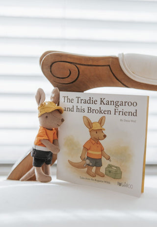 Book titled 'The Tradie Kangaroo and his Broken Friend' with a toy kangaroo wearing a hard hat on a white surface.