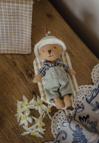 A small rugaroo wombat farmer doll is relaxing on a miniature dollhouse-sized striped hammock.