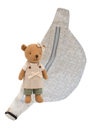 A small plush barista wombat doll wearing a cream apron and green shorts, posed in front of a matching beige floral fabric bum bag with a silver zipper on a white background.