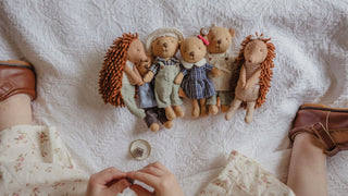 A top-down view of a child's hands and legs interacting with a Rugaroo miniature Australian animal dolls like echidnas and wombats.