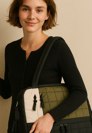 Woman holding a green and black baby bag against a beige background