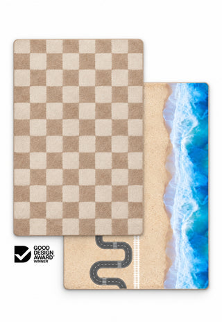 Rugabub Biscuit / Ocean Road reversible baby play mat showing a soft neutral biscuit and cream checkerboard rug design on one side and a beach play map with winding road, train track and ocean waves on the other
