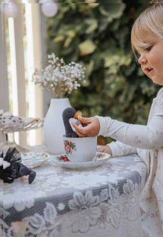 Young girl playing with Byron the Rugaroo black swan plush doll in a vintage tea cup; imaginative play with Australian heirloom miniature toy