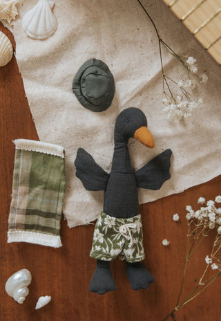 Flat lay of Byron the Rugaroo black swan plush doll with his green boardies, sun hat and beach towel -  heirloom Australian miniature doll with accessories