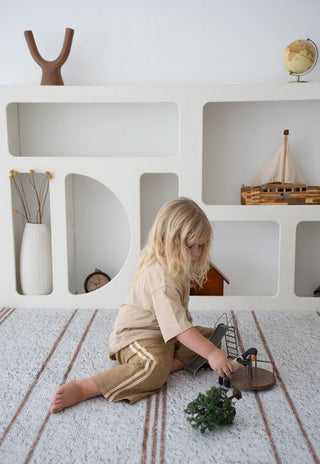 Child playing with toys on Rugabub Cala neutral striped foam baby play mat.