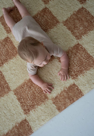 Baby playing on soft padded Phoenix checkered foam baby play mat by Rugabub.