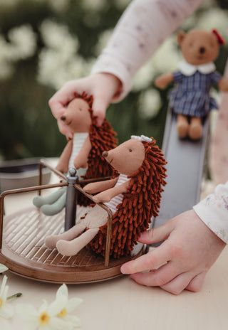 Girl playing with Col and Riva the Rugaroo echidna dolls on the roundabout beside the miniature slide