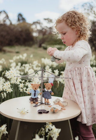 Girl playing with two Rugaroo Prep Wombat dolls and a dollhouse clothesline hoist toy