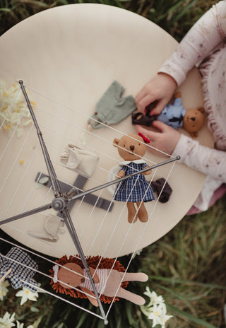 Girl playing with a Rugaroo wombat doll underneath a backyard hoist toy