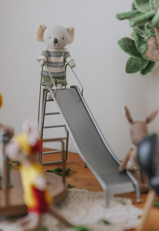 Toy miniature slide with a koala bear on a ladder in a child's playroom.