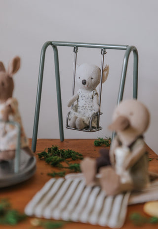 miniature koala doll sitting in a miniature metal swing toy for kids