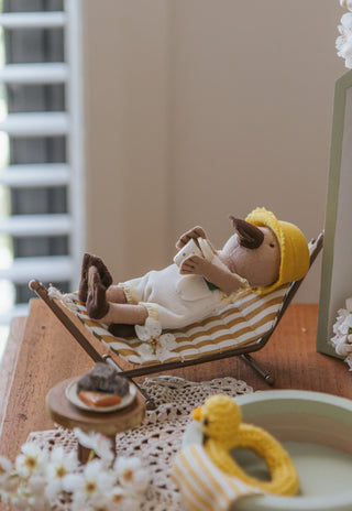 miniature dollhouse hammock with wavy pattern on a stand with a miniature platypus doll sipping pretend coffee