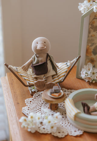 miniature dollhouse hammock with wavy pattern on a stand with a miniature platypus doll