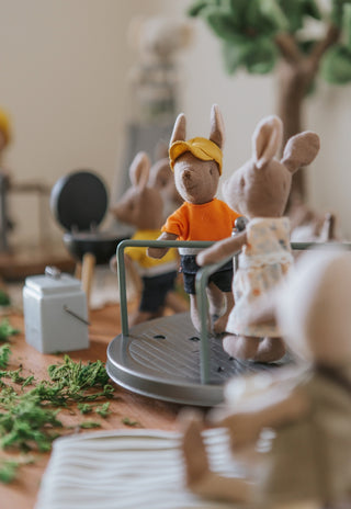 two miniature dollhouse toys on a merry-go-round