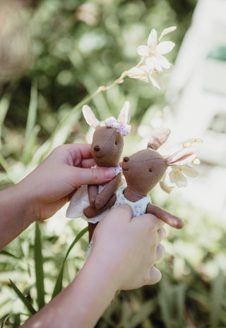 Close up of hands holding Mon the Bae in a white lace dress and Betty the Bush Belle in a bluebell floral dress, Rugaroo kangaroo dolls