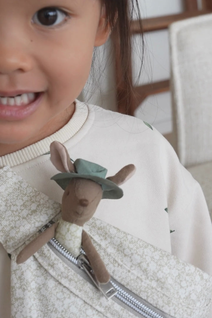 a girl wearing a rugaroo pouch bag and Shaz the Rugaroo kangaroo doll inside of it