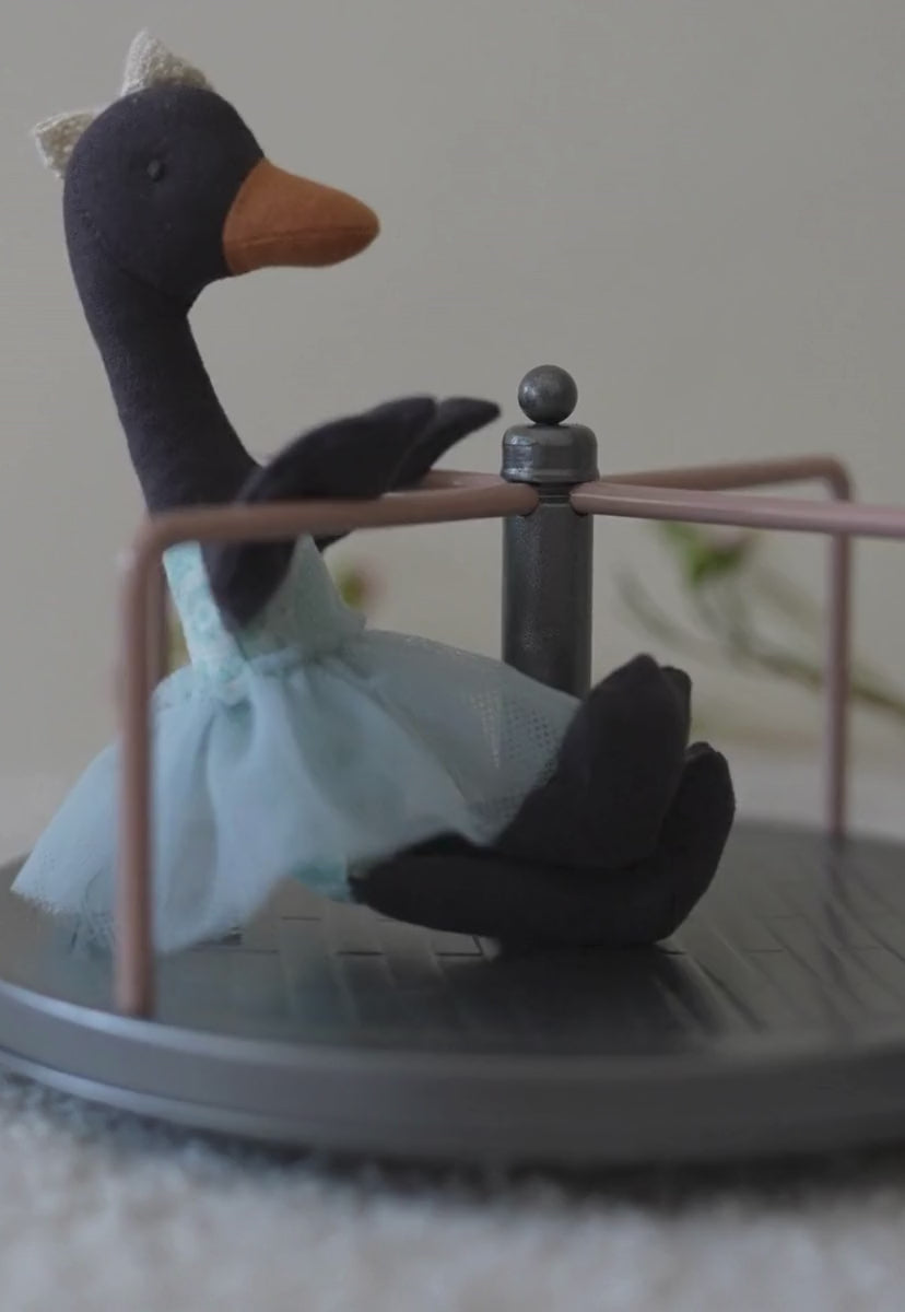 Black swan doll from Rugaroo spinning om a Carousel or Round-a-bout