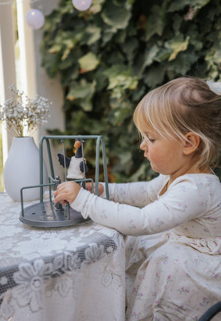 Young girl playing with Reed the Rugaroo Wetlands Ranger black swan plush doll on a miniature swing set — Australian heirloom toy for imaginative play