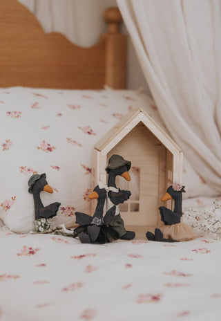 The Rugaroo Black Swan collection arranged around a wooden toy house on a floral kids bed - premium Australian miniature plush dolls for dollhouse play