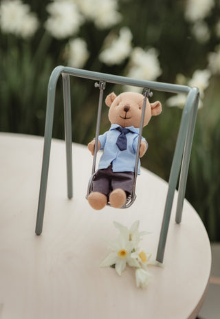 Clancy the Prep Wombat doll from Rugaroo swinging on a dollhouse-scale miniature swing