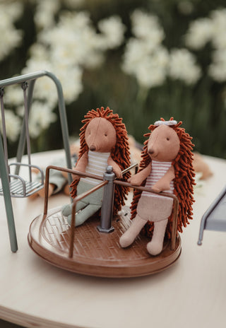 Col and Riva the Rugaroo echidna dolls playing on a miniature brown roundabout carousel