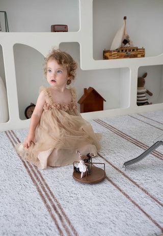 Soft padded Rugabub Cala neutral striped foam baby play mat with child playing.