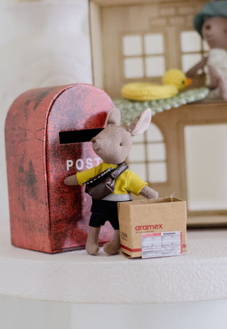 Stuffed toy kangaroo postman with a shipping box in front of a red mailbox