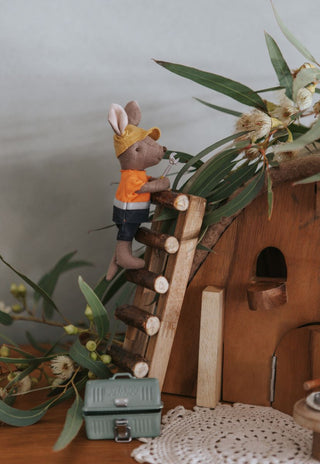 A dollhouse with a Rugaroo Tradie Kangaroo climbing a miniature ladder with a tool in his hand