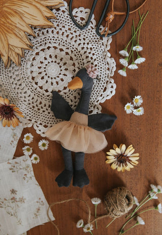 Flatlay of Wattle the Bush Florist Rugaroo black swan doll surrounded by Australian wildflowers and daisies - heirloom miniature plush toy inspired by native flora