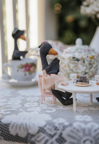 Wattle the Bush Florist Rugaroo black swan doll seated at a miniature tea party table - premium Australian plush toy for dollhouse and small-world play