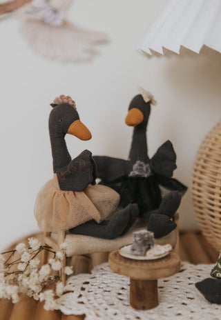Wattle and Maali Rugaroo black swan heirloom plush dolls sitting on a miniature couch with lamingtons - Australian collectible toys styled in a children's room